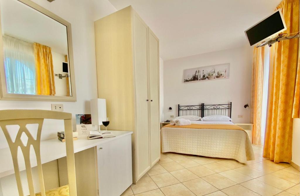 Mūsdienīga viesnīcas numura iekārtojums ar gultu, rakstāmgaldu un televizoru. Telpā ir gaišas krāsas un dabiska apgaismojuma efekts.