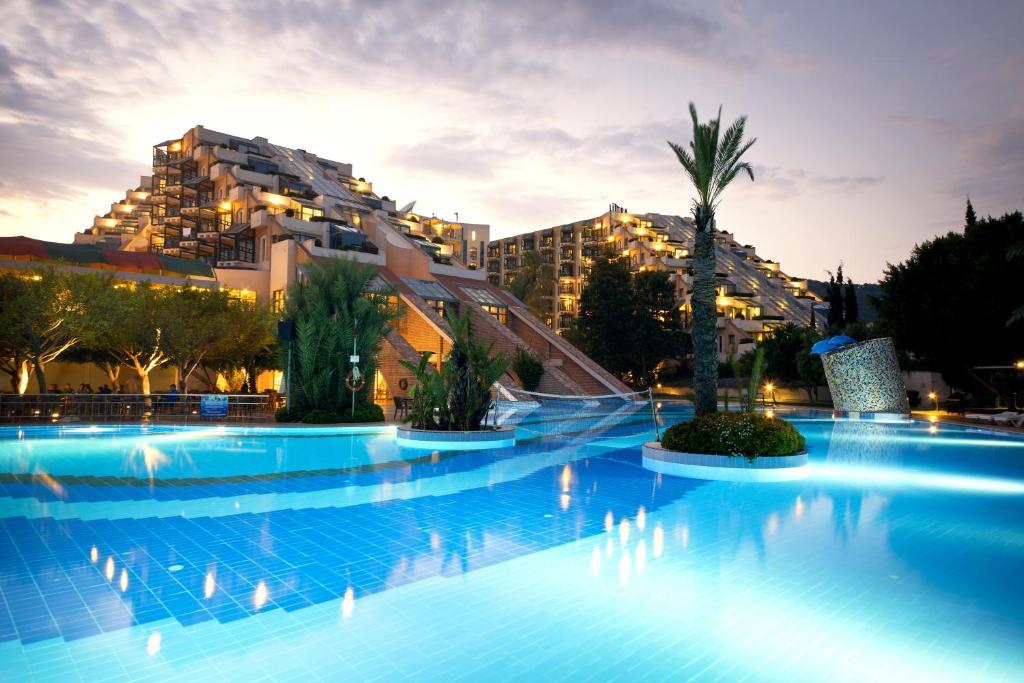 Limak Limra Hotel & Resort baseins piekrastē vakarā ar apgaismojumu.