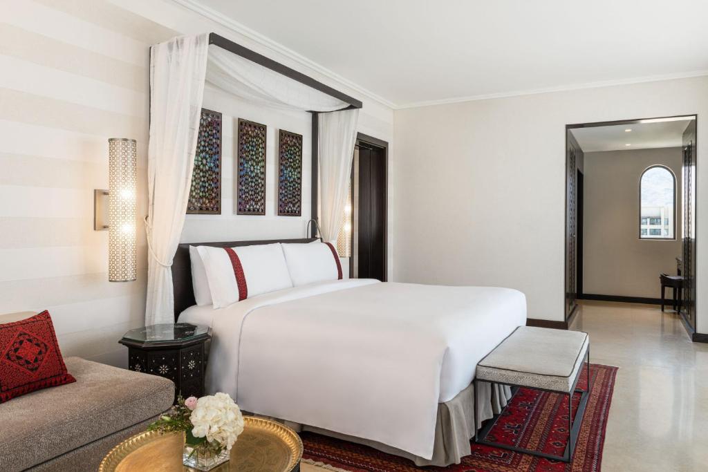 Mūsdienīgs guļamistabas interjers ar elegantu gultu, stilīgu apgaismojumu un dekoratīvām sienu gleznām, radot komfortablu un estētisku atmosfēru.