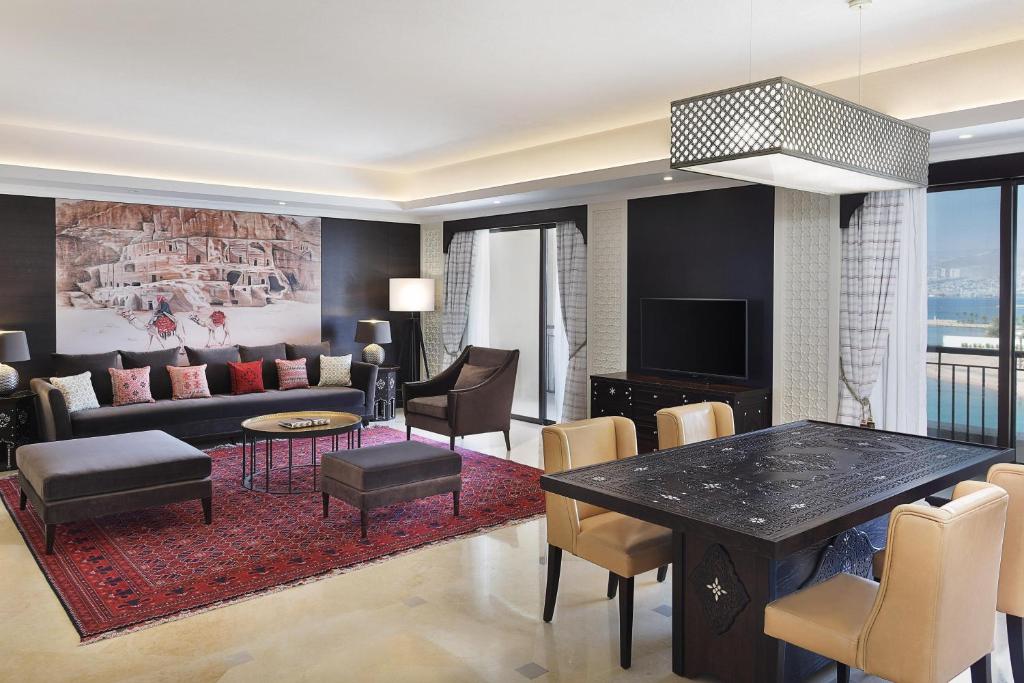 Mūsdienīgs viesistabas interjers ar elegantām mēbelēm, siltām krāsām un izsmalcinātu apgaismojumu. Sienā redzama mākslinieciska gleznas reprodukcija, kas piešķir telpai unikālu raksturu.