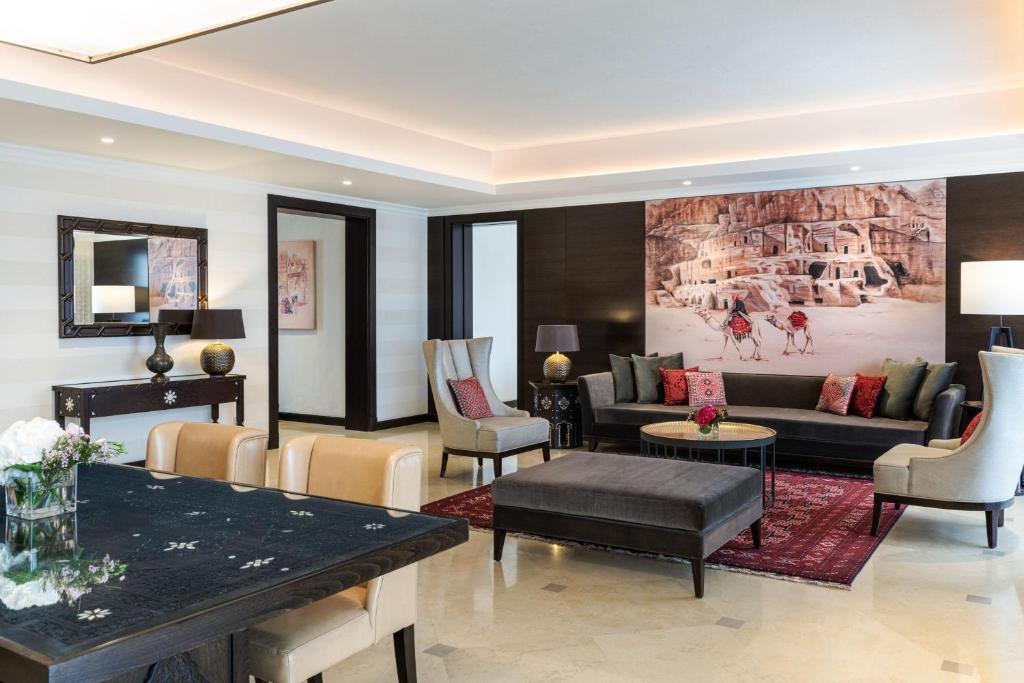 Mūsdienīgs viesistabas interjers ar elegantiem mēbeļu risinājumiem, rakstainu paklāju un mākslas darbu uz sienas. Izteikta gaisma un silta atmosfēra.