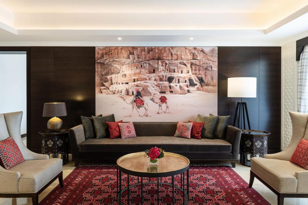 Mūsdienīga viesistaba ar elegantu dizainu, kas ietver mākslas darbu uz sienas, kas attēlo vēsturiskas ainavas, un stilīgas mēbeles ar sarkaniem akcentiem. 