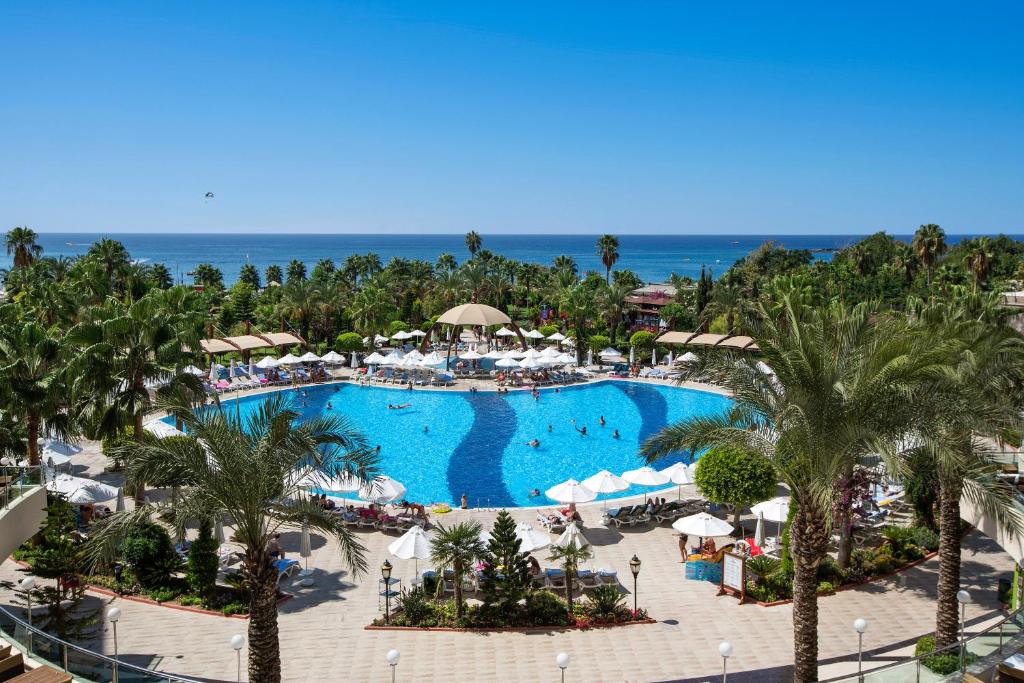 Saphir Resort & Spa baseins ar zilo ūdeni un palmu kokiem piekrastē.