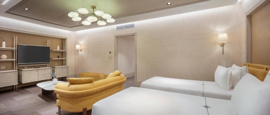 Mūsdienīgs numurs ar divām gultām un dzeltenu dīvānu Ela Excellence Resort Belek.