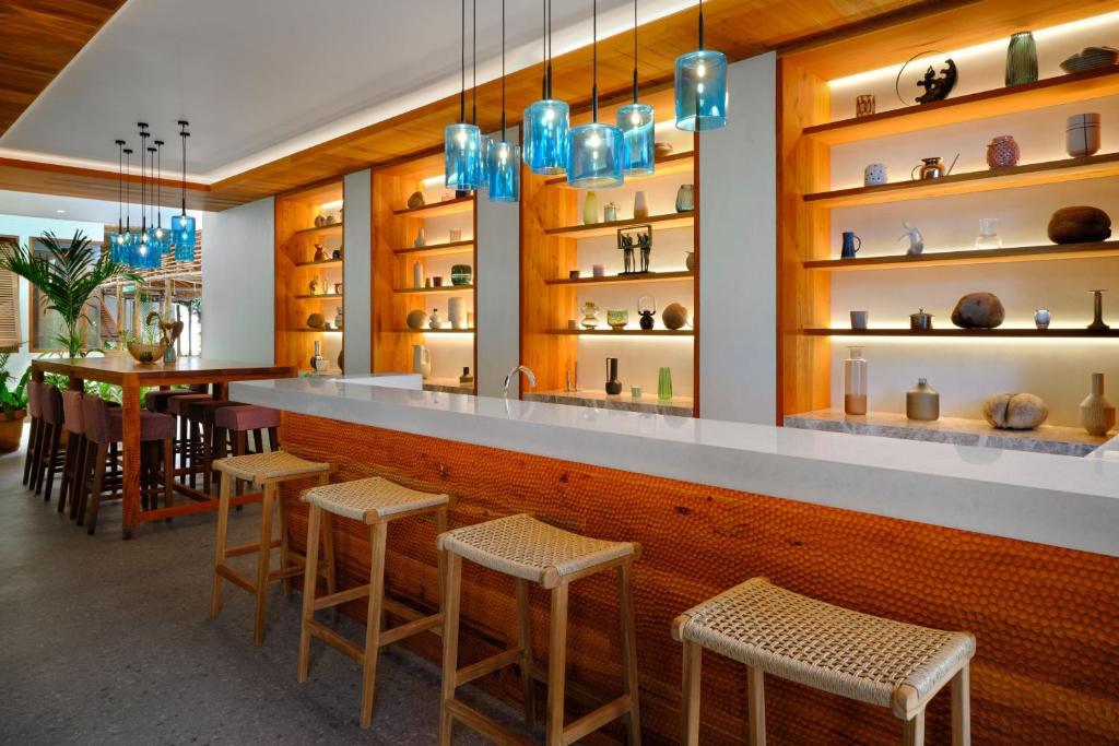 Mūsdienīgs bārs ar koka interjeru, kas izceļs ar stikla lampām un dekoratīvām vitrīnām, kurās ir izvietoti mākslas priekšmeti un podi. Bāra zona ir ērta, ar augstām krēslām un atvērtu atmosfēru.