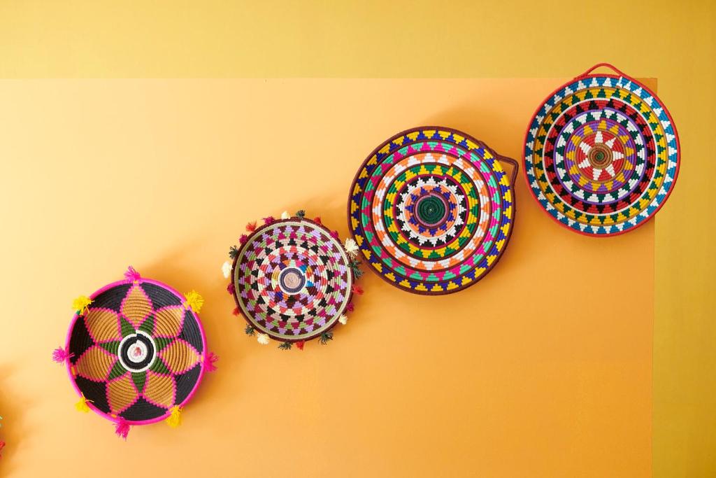 Krāsaini, roku darbs izstrādājumi, kas novietoti uz dzeltenas sienas, radot dzīvīgu un mājīgu atmosfēru. Šie trauki ir grezni izstrādāti ar dažādām ģeometriskām formām un krāsām.