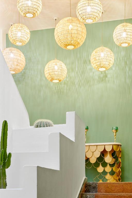 Moderns interjers ar zaļu sienu, stilizētu lampu un dekoratīvu galdu. Svaiga un gaisīga atmosfēra ar augu elementiem.