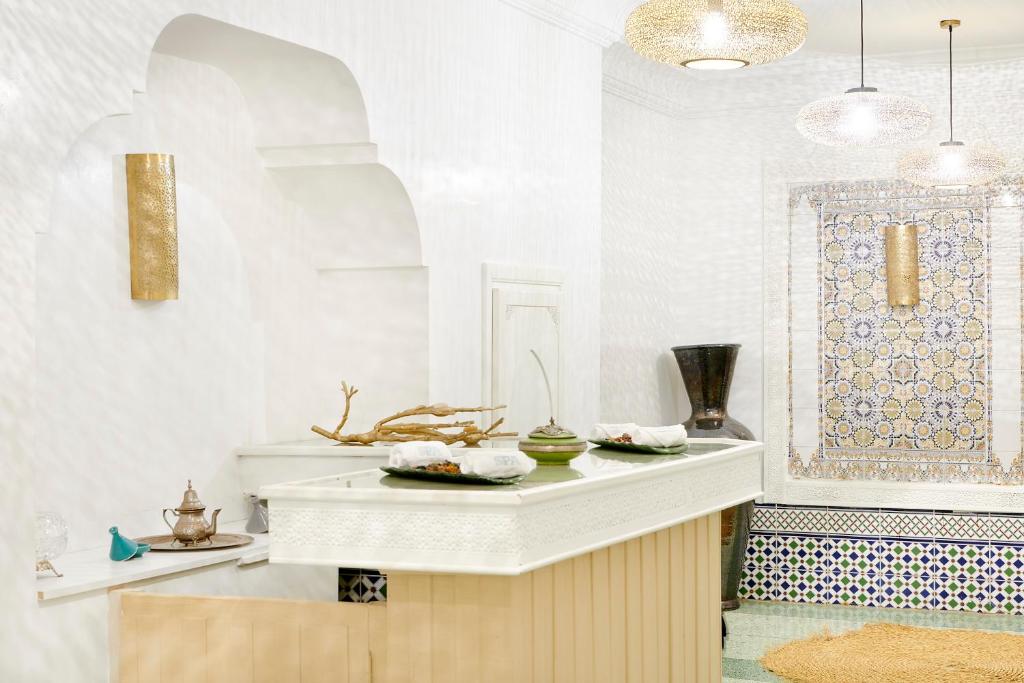 Mūsdienīga un eleganta telpa ar baltām sienām, dekoratīvām lampām un tradicionālu mozaīku. Interjerā redzama stilīga recepcija ar dekoratīviem elementiem, kas rada relaksējošu atmosfēru.