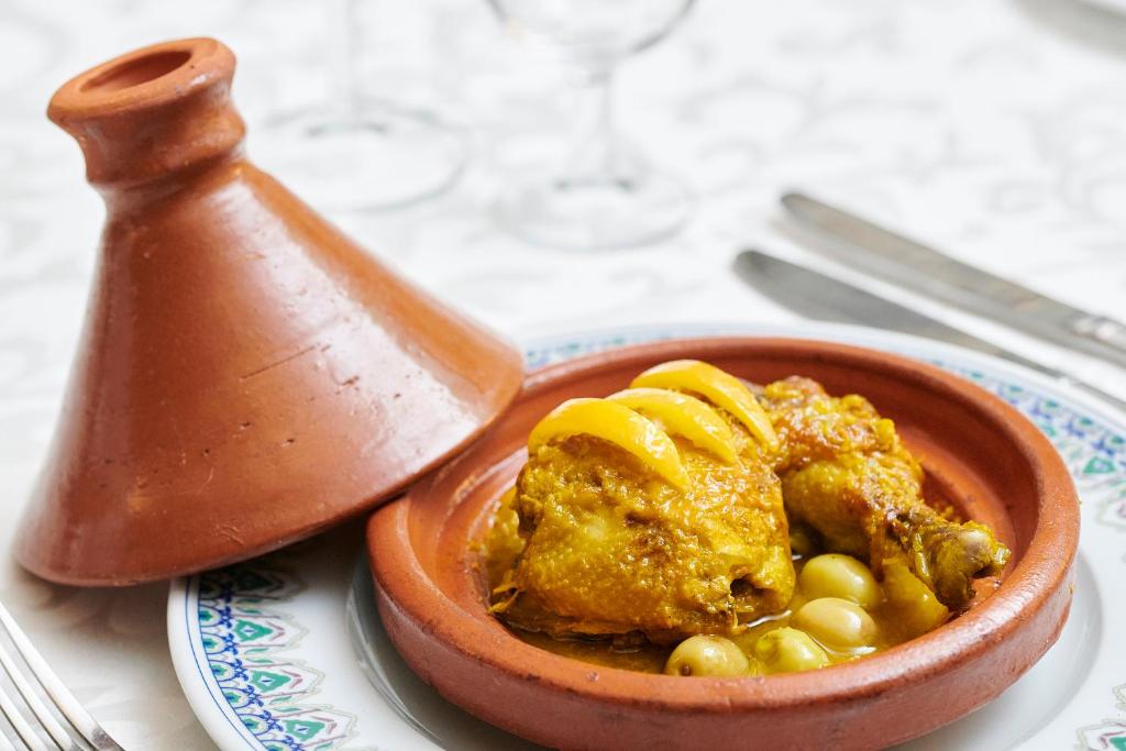 Tradicionāls marokāņu tagine ar vistu, olīvām un citroniem, pasniegts keramikas traukā.