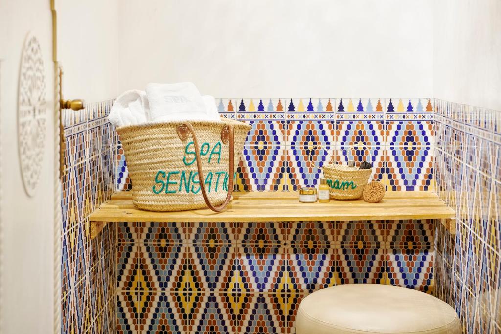 Mūsdienīgs spa stūris ar krāsainiem flīzēm, koka plauktu un grozu ar dvieļiem. Ideāla vide relaksācijai un labsajūtai.