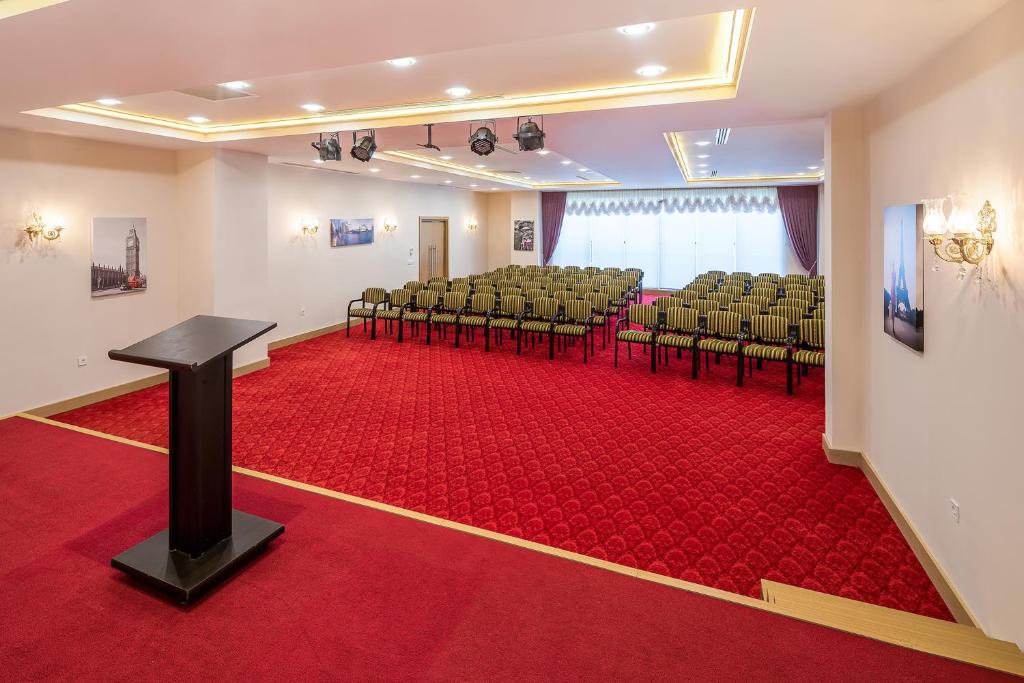Konferenču telpa L'oceanica Beach Resort Hotel ar sarkanu paklāju un sēdvietām.
