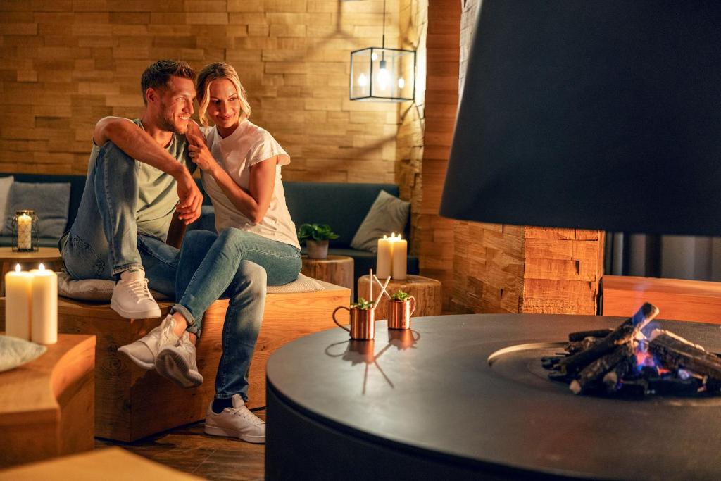 Siltā un mājīgā interjerā pāris bauda romantisku brīdi pie kamīna, apgaismojot telpu ar sveču gaismu un kopā pavadītu laiku.
