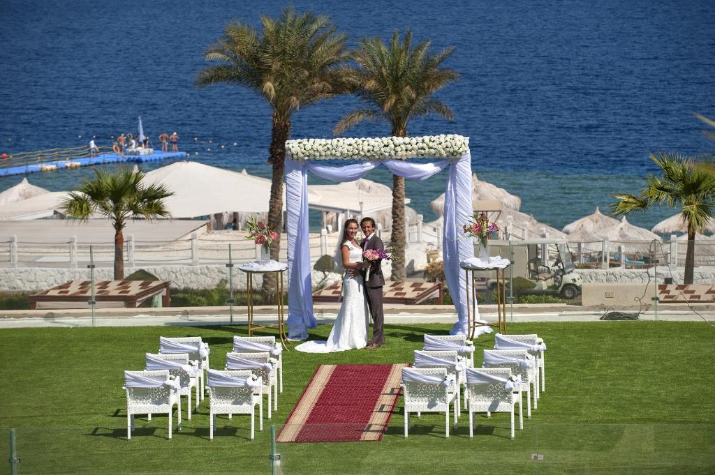 Kāzu ceremonija Sunrise Arabian Beach Resort piekrastē ar ziedu arkām.