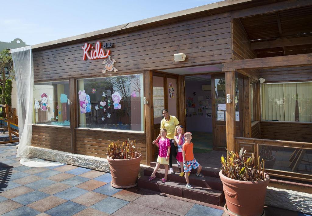 Bērnu klubs Sunrise Arabian Beach Resort ar laimīgiem bērniem un darbinieku.