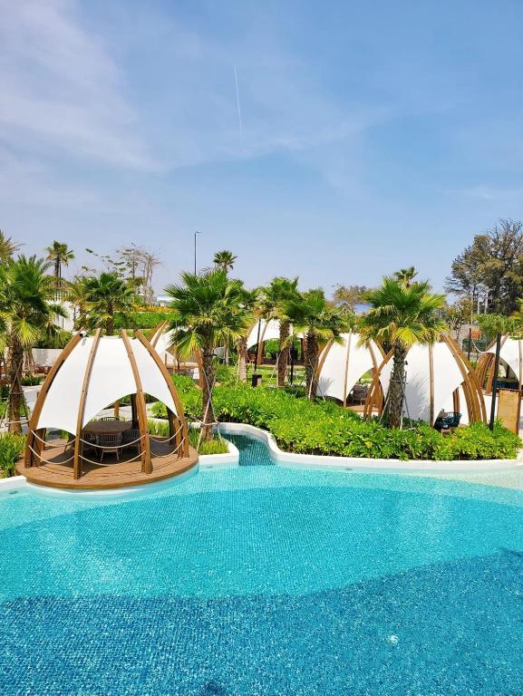 Peldbaseins ar modernām atpūtas zonām, kuras ieskauj palmas un zaļumi, radot relaksējošu un tropisku atmosfēru. Ideāla vieta atpūtai un izklaidei.