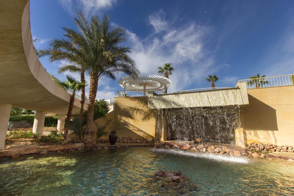 Dabiskā oāze ar ūdens kritumu, palmu kokiem un modernu arhitektūru, kas rada relaksējošu atmosfēru. Ideāla vieta atpūtai un dabas baudīšanai.