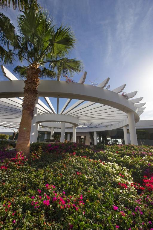 Mūsdienīgas arhitektūras elements ar apaļu jumtu un krāšņiem ziediem priekšplānā, kas radījuši patīkamu atmosfēru.