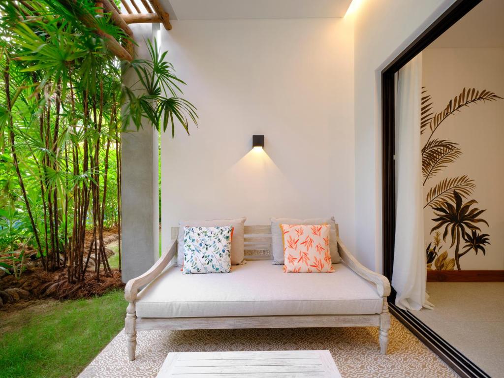 Mūsdienīgs terases stūris ar komfortablu dīvānu un spilveniem, ko ieskauj zaļumi un tropisku augu motīvi. Ideāla vieta relaksācijai un dabas baudīšanai.