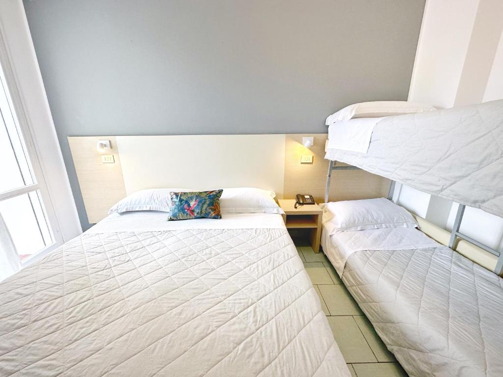 Mūsdienīgs viesnīcas numurs ar divguļamo gultu un divkāršo gultu, dekorēts ar spilvenu ar tropisku motīvu. Gaismas tonis un vienkāršs dizains rada komfortablu atmosfēru.