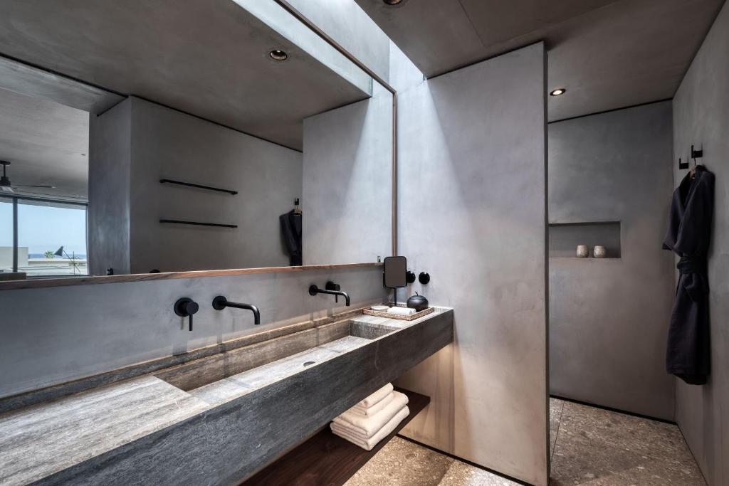 Mūsdienīgs vannas istabas interjers ar betona sienām, elegantu izlietni un minimālistisku dizainu. Pievilcīgs apgaismojums un mūsdienīgas detaļas rada relaksējošu atmosfēru.