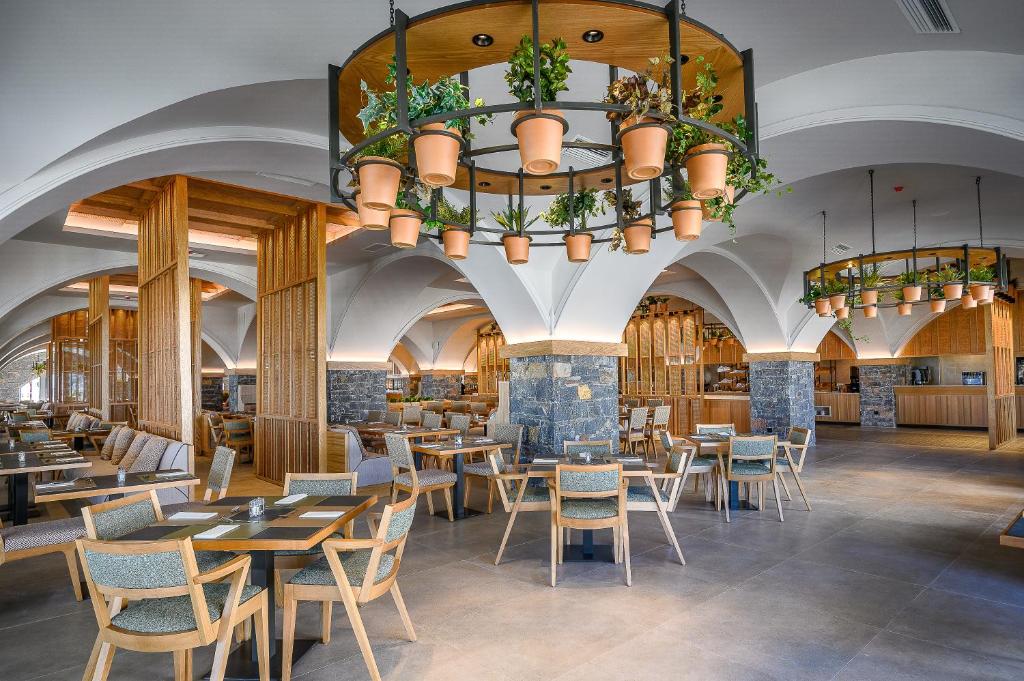 Moderns restorāns ar elegantu interjeru, kur dominē koka un akmens elementi, kā arī piekārtie ziedu podi, radot patīkamu un relaksējošu atmosfēru.
