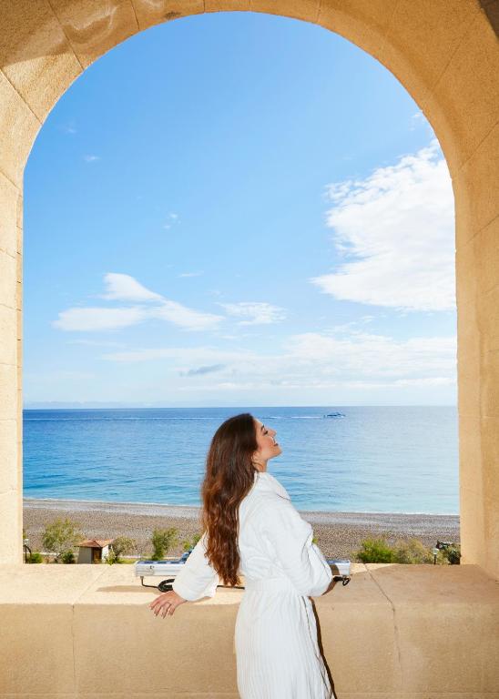 Sieviete baltā halātā, skatoties uz jūru pie Grande Albergo Delle Rose.