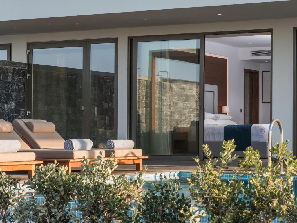 Mūsdienīga viesnīcas istaba ar plašām stikla durvīm, divām sauļošanās krēslām un peldbaseinu, ko ieskauj zaļumi. Ideāla vieta atpūtai un relaksācijai.