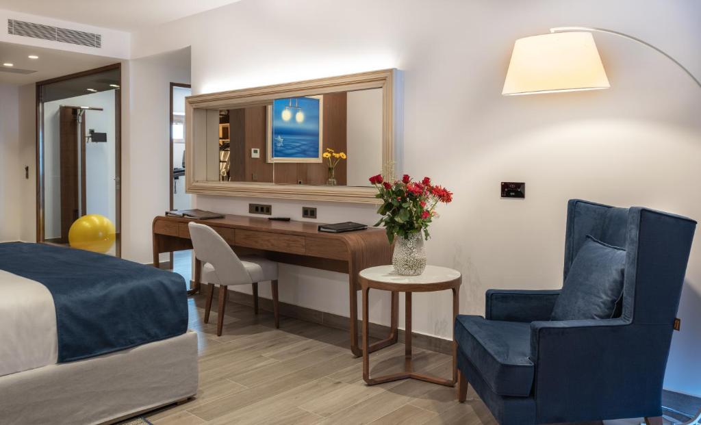 Mūsdienīgs viesnīcas numurs ar ērtu gultu, rakstāmgaldu un zilu krēslu, dekorēts ar ziedu pušķi un mākslas darbu uz sienas. Gaismas krēsls un dzeltenais bumba piešķir telpai dzīvīgumu.