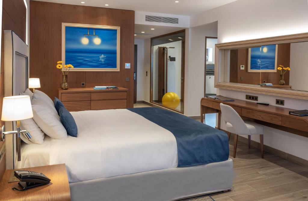 Mūsdienīgs, elegants guļamistabas interjers ar zilu gultas pārklāju un koka mēbelēm, kas papildināts ar mākslas darbu uz sienas un saulespuķēm uz galda. Guļamistabā ir arī rakstāmgalds un spogulis.