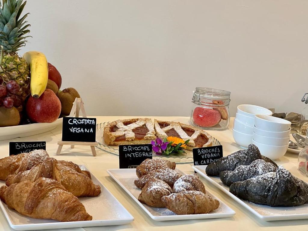 Saldumu galda izkārtojums ar dažādām maizītēm, tostarp vegāniskām brioche un augļiem. Iekļauti arī dekoratīvi elementi un trauki.