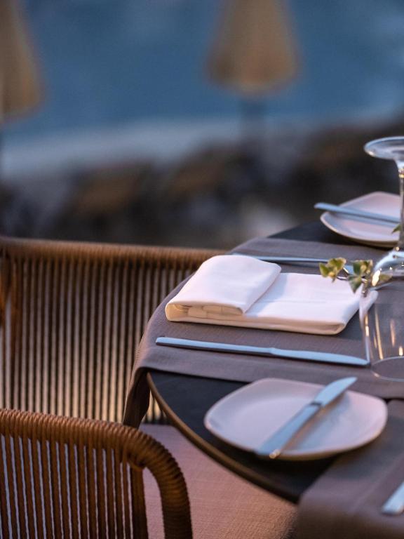 Elegants galda iestatījums ar baltām salvetēm un galda piederumiem, kas atrodas uz tumša galda. Fons ir izpludināts, radot mierīgu atmosfēru.