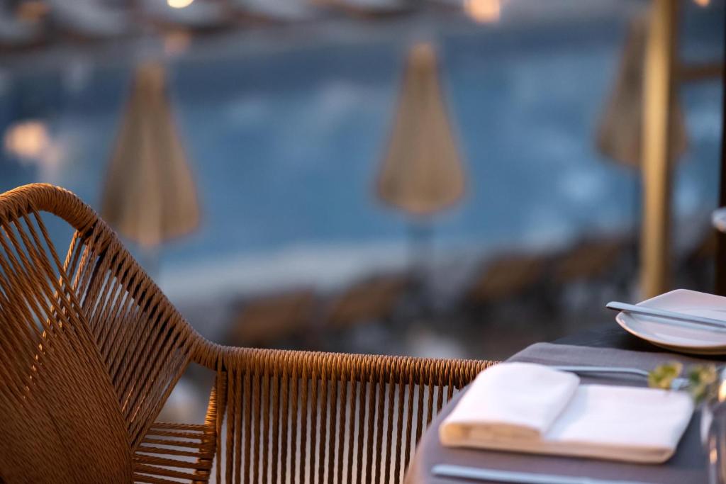 Rūpīgi iekārtota galda skats ar rotāto krēslu un peldbaseinu fona. Elegants restorāna interjers ar modernu dizainu un relaksējošu atmosfēru.