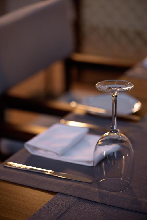 Eleganta galda klāšana ar glāzi, salveti un galda piederumiem, radot viesmīlīgu atmosfēru.