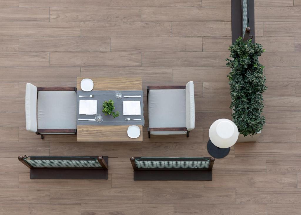 Mūsdienīgs ēdamgalds ar krēsliem, sakārtots ar galda piederumiem un augu dekorāciju, redzams no augšas. Eleganta telpa ar koka grīdu un minimālistisku dizainu.