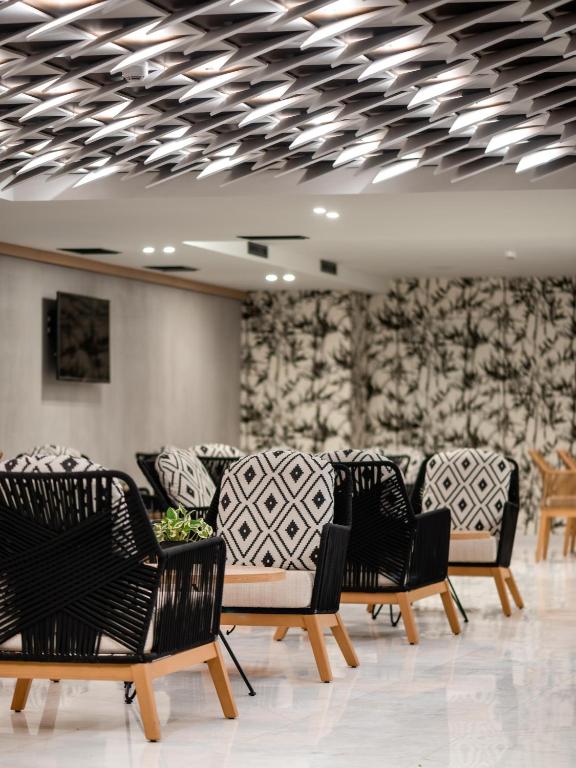 Mūsdienīgs interjers ar stilīgiem krēsliem un rakstainām sienām, radot elegantu un aicinošu atmosfēru. Gaismekļu dizains papildina telpas estētiku.