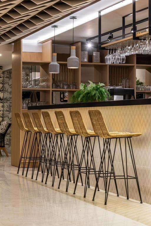 Moderns bārs ar augstām krēslām un elegantu interjeru, kas ietver koka un metāla detaļas. Labi apgaismots ar piekaramām lampām, kas piešķir siltumu telpai.