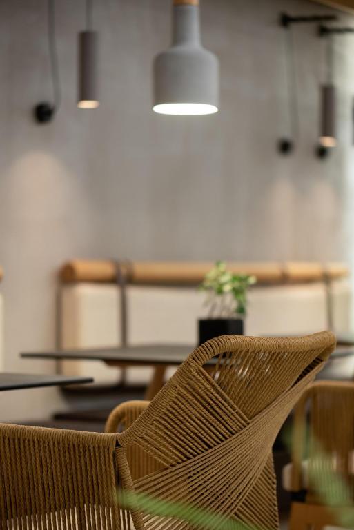 Mūsdienīga kafejnīca ar elegantu dizainu, kurā redzami vērsti gaismas ķermeņi un ērti krēsli. Interjerā ir izmantoti dabīgi materiāli un zaļumi, kas papildina atmosfēru.