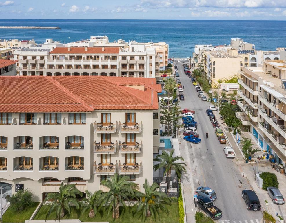 Pilsētas ainava ar viesnīcu, blakus pludmalei un jūrai, viesnīcas balkoni un zaļumi uz priekšu.