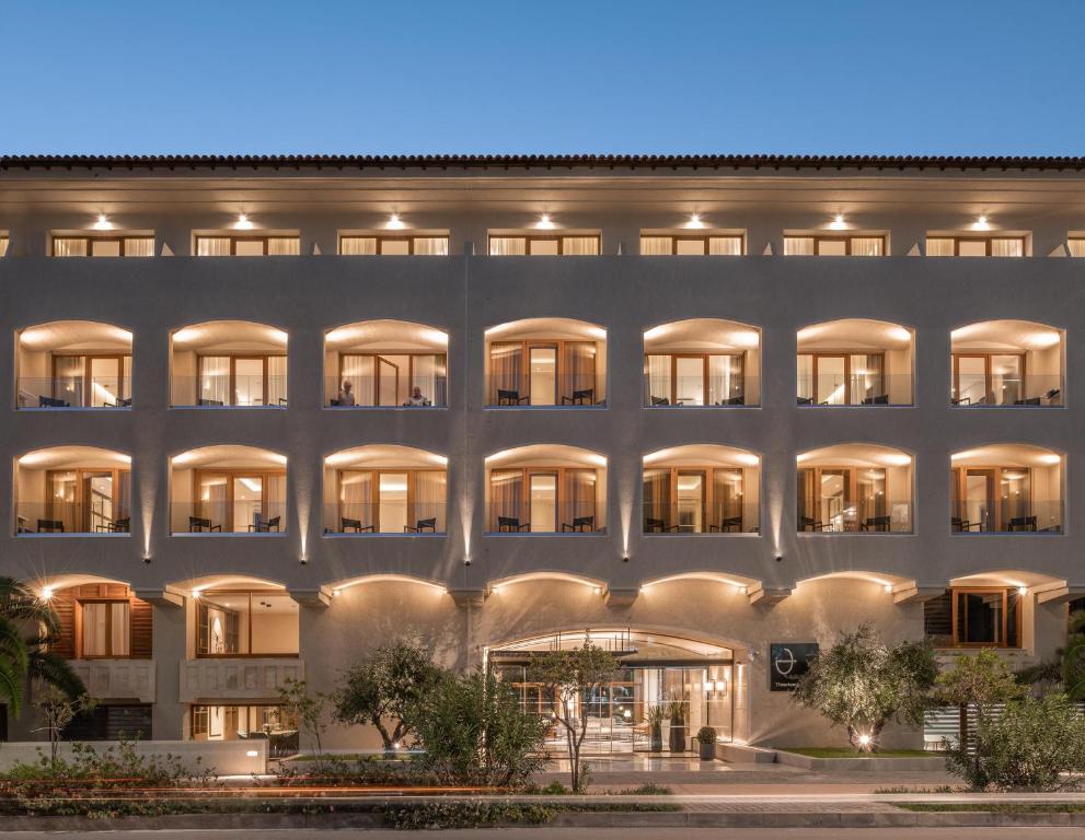 Moderns viesnīcas fasādes skats ar apgaismojumu un balkoniem, kas nodrošina komfortablu atpūtu. Apkārtne ir rūpīgi kopta ar zaļumiem un ainavu.