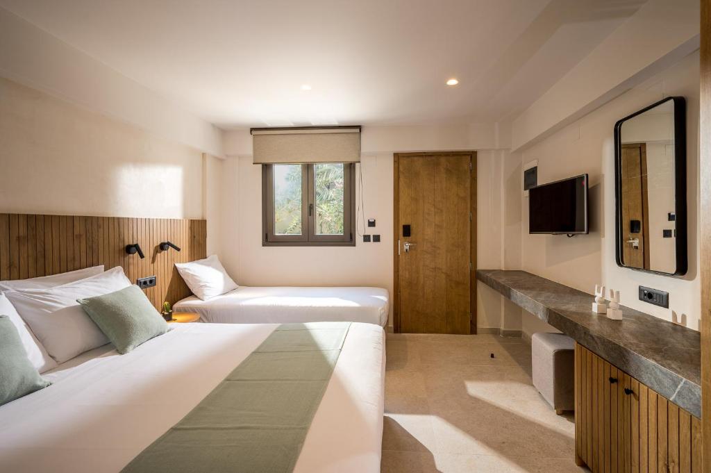 Mūsdienīgs viesnīcas numurs ar divām gultām, koka akcentiem un televizoru, kas piedāvā komfortablu un stilīgu atpūtu. Logā redzama dabas ainava, radot patīkamu atmosfēru.