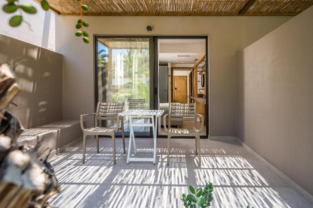 Mūsdienīgs terases stūris ar divām krēslām un galdu, kas izvietots zem laukuma jumta, radot patīkamu un ērtu atmosfēru. Daba redzama caur stikla durvīm, piešķirot telpai dzīvīgumu.