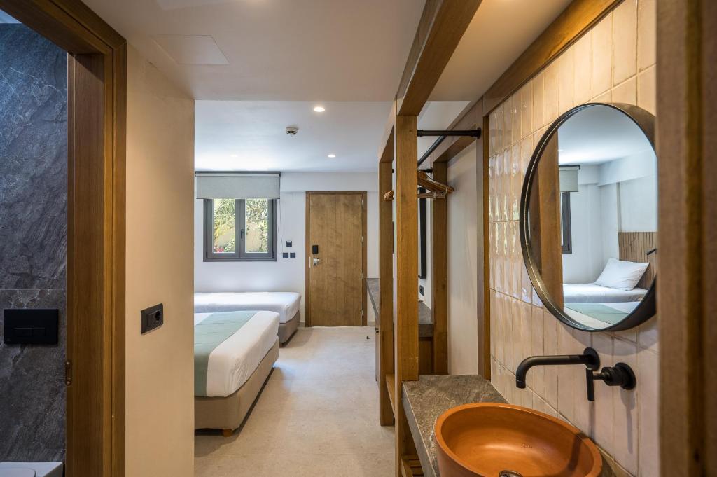 Mūsdienīgs viesnīcas numurs ar divām gultām, koka un akmens elementiem, kā arī apaļu spoguli. Telpa ir gaiša un plaša, radot komfortablu atmosfēru.