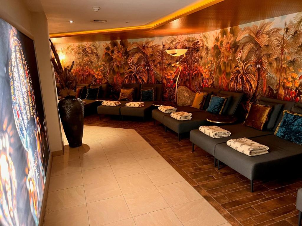 Mūsdienīgs relaksācijas stūris ar ērtām dīvāniem, dekorēts ar krāšņām augu un ziedu sienām. Telpā ir spilgti aksesuāri un siltas gaismas, kas rada mierīgu atmosfēru.