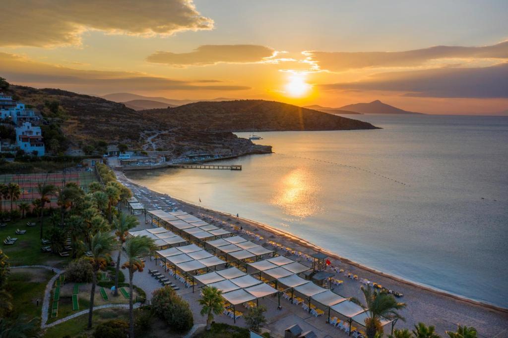 Saulriets pie pludmales Kairaba Bodrum Imperial ar palmām un atpūtas zonām.