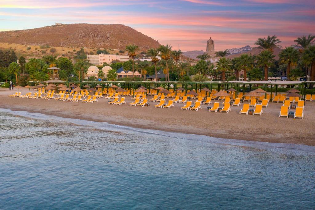 Kairaba Bodrum Imperial pludmale ar sauļošanās krēsliem un palmu kokiem
