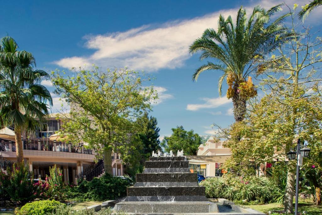 Kairaba Bodrum Imperial viesnīca ar strūklaku un tropiskiem kokiem.