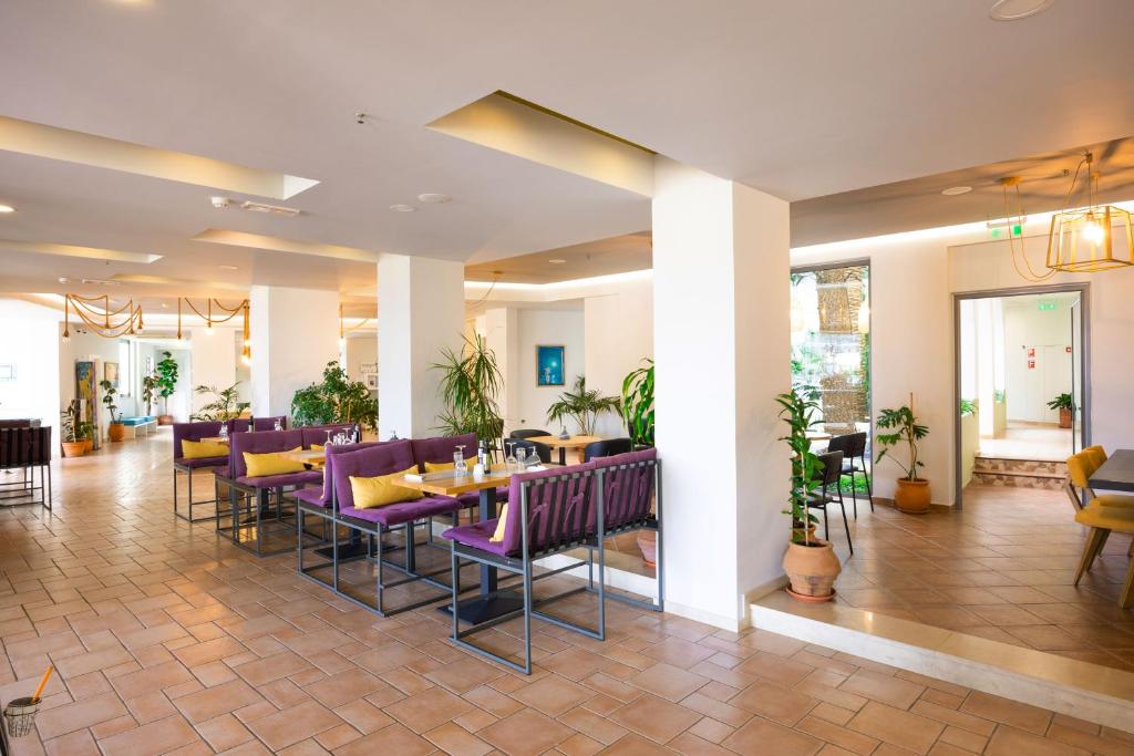 Mūsdienīgs restorāna interjers ar atvērtu plānojumu, kurā ir ērtas sēdvietas un zaļumi, radot patīkamu atmosfēru. Apgaismojums un dizains piešķir telpai siltumu un viesmīlību.