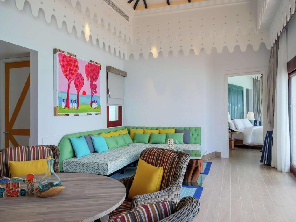 Mūsdienīgs viesnīcas numurs ar spilgtu interjeru, iekārtots ar krāsainām dīvāna spilveniem un mākslas darbu uz sienas. Numurā ir gaišas krāsas un liels logs, kas nodrošina dabisko apgaismojumu.