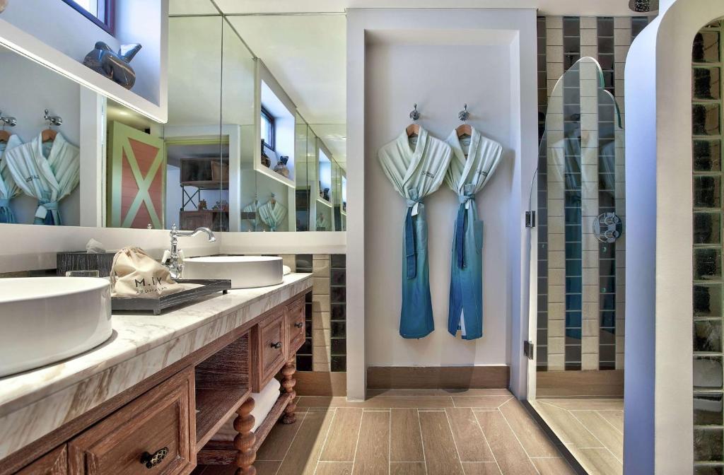 Mūsdienīgs vannas istabas interjers ar diviem peldmēteļiem, modernām izlietnēm un spoguļiem, kas atspoguļo elegantu dizainu un funkcionālu izkārtojumu.