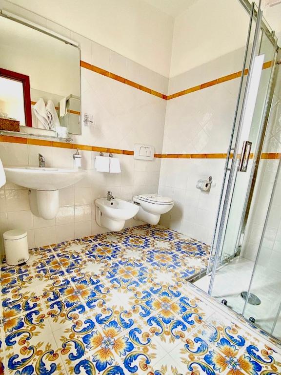 Vannas istaba ar krāsainu flīžu grīdu, dušu un sanitārajiem mezgliem, kas nodrošina funkcionālu un estētisku vidi.